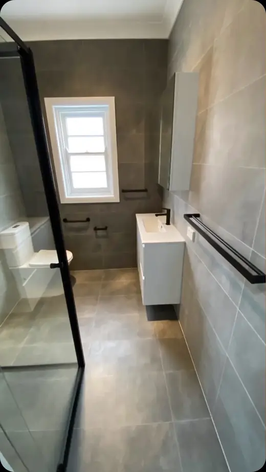 Renovated bathroom with black fittings and a framed glass shower
