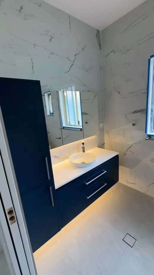 Renovated bathroom with a navy vanity and stone-look tiles