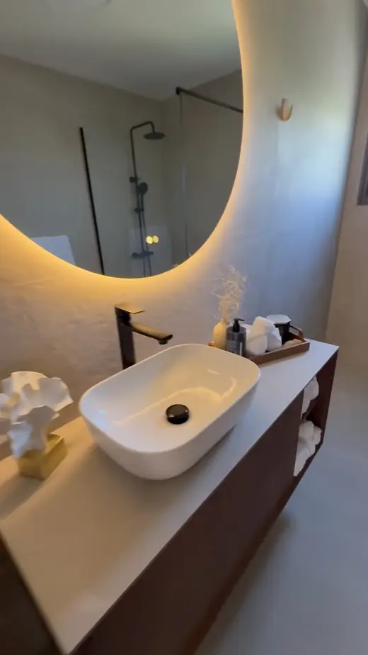 Renovated bathroom with a round backlit mirror and floating vanity