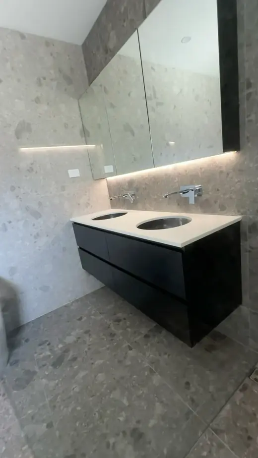 Renovated bathroom with terrazzo-look tiles and a black vanity