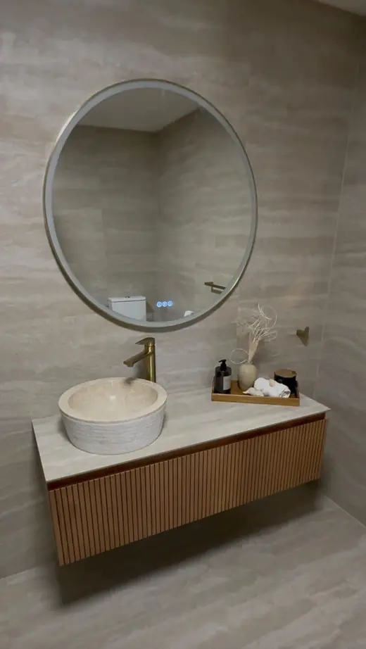 Renovated bathroom with a round mirror and timber vanity