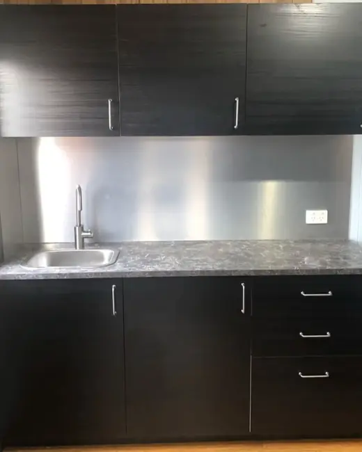 Kitchen with dark cabinets and a stainless splashback