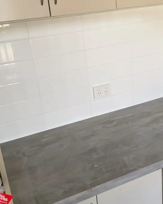 Kitchen with a white tiled splashback and new benchtop