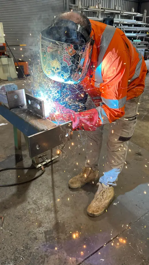 Welder in hi-vis welding steel with sparks flying